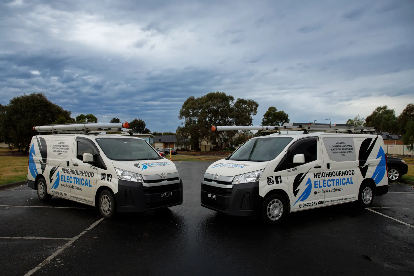 Two Neighbourhood Electrical service vans in parking lot.